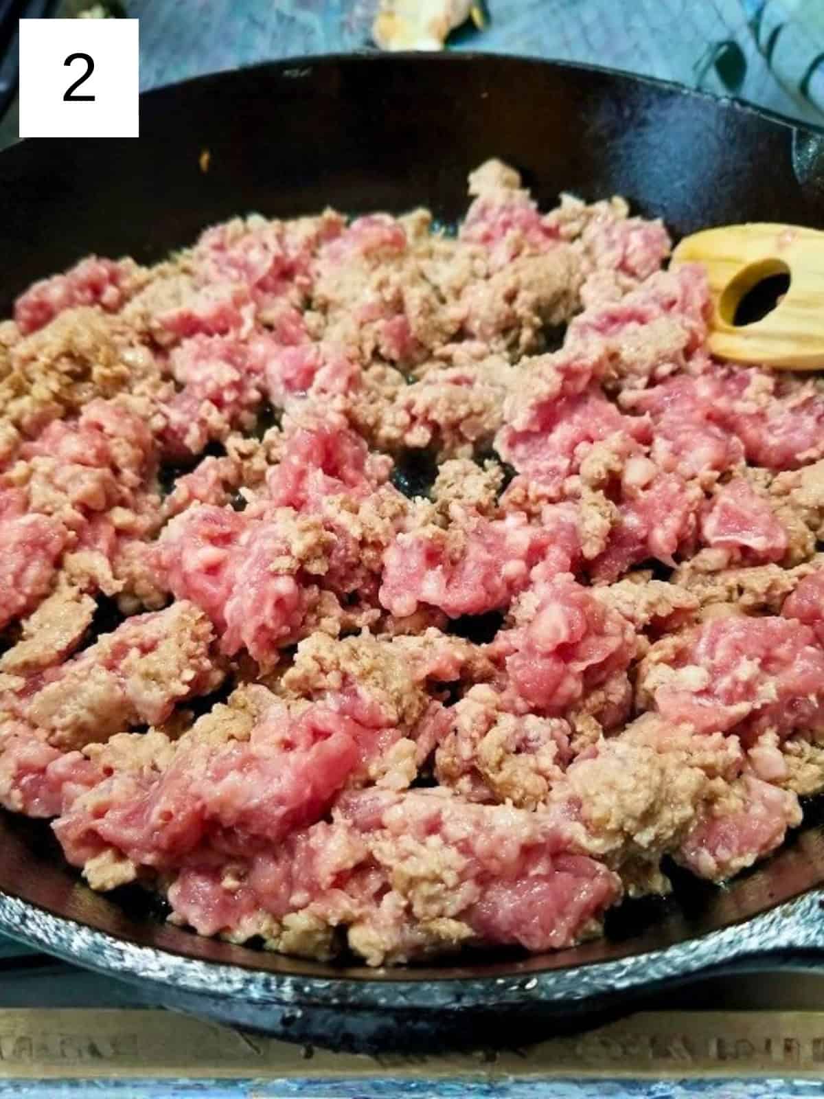 Raw ground chicken in a cast iron pan.