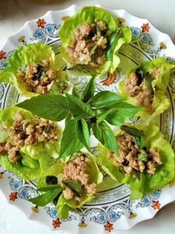 Lettuce wraps made with ground chicken, fresh herbs, garlic, and ginger, on a plate.