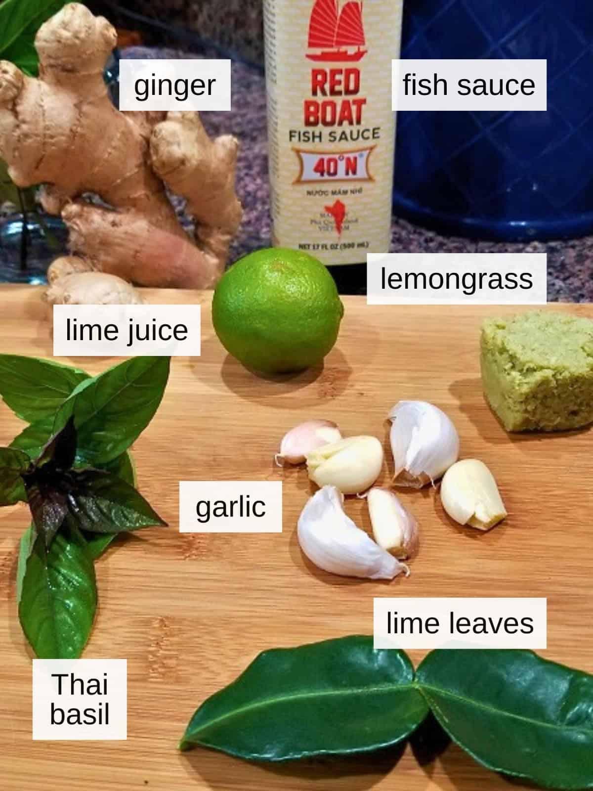 Ingredients for lettuce wraps, including fresh ginger for ginger puree, fish sauce, lime juice, Thai basil leaves, fresh garlic, lime leaves, and lemongrass.